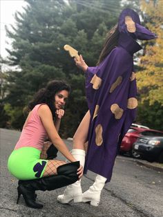 two women dressed in costumes kneeling down on the street