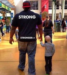 a man holding the hand of a little boy as they walk through an indoor mall