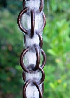 a close up of a chain hanging from a window sill with rain coming down