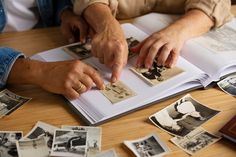 two people touching pictures on top of an open book with other photos in the background