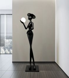 a black statue holding an apple in it's hand and standing next to a white wall