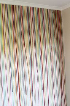 a bed sitting under a window next to a wall covered in multicolored stripes