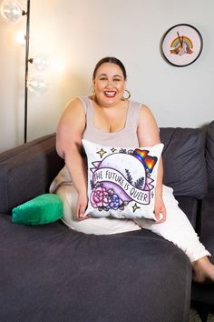 a woman sitting on top of a couch holding a pillow