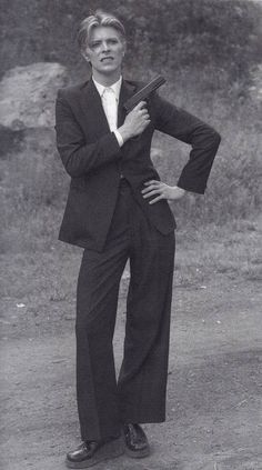 an old photo of a man in a suit and tie standing with his hands on his hips