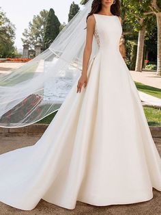 a woman in a white wedding dress posing for the camera with her veil over her head