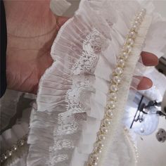 a woman's hand is holding some pearls and lace on her wedding dress,