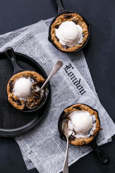 two desserts with ice cream on top are sitting on a black plate next to a spoon