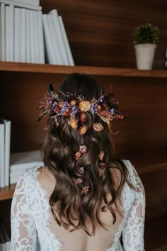 the back of a woman's head with flowers in her hair and lace sleeves