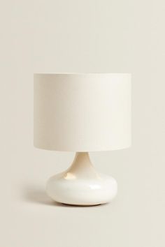 a white table lamp with a white shade on the top and bottom part of it