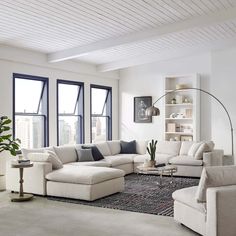 a living room filled with white furniture and large windows in the wall next to each other