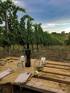 two wine glasses sitting on top of a wooden table next to a bottle of wine