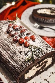 a piece of cake on a white plate with berries and powdered sugar sprinkled on top