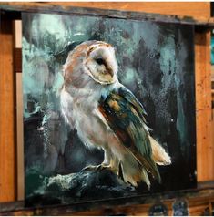 an owl is sitting on top of a piece of wood in front of a painting