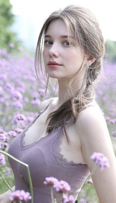 a young woman standing in a field of flowers with her hair pulled back and eyes closed