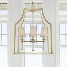 a chandelier hanging from the ceiling in a room with windows and white curtains