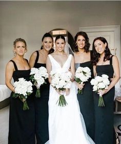 a group of women standing next to each other in front of a mirror holding bouquets