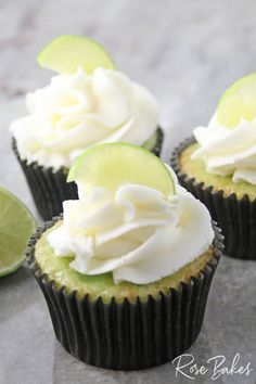 three cupcakes with lime slices and whipped cream on top are sitting on a table