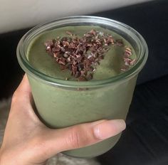 a hand holding a green smoothie with chocolate sprinkles