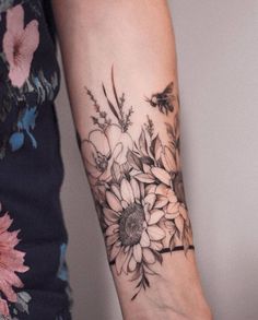 a woman's arm with flowers on it and a bee flying around the wrist