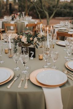 the table is set with white and gold place settings, silverware, candles, and flowers