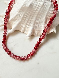 a red beaded necklace sitting on top of a white shell