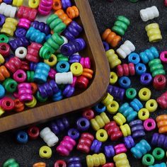 there are many different colored beads on the floor next to a wooden tray with one bead in it