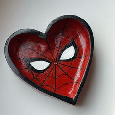 a heart shaped bowl with a spiderman face painted on it