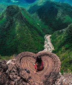 a woman sitting on top of a wooden structure in the middle of a mountain range