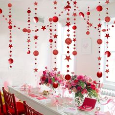 the table is set with pink and red decorations on it, along with hanging ornaments