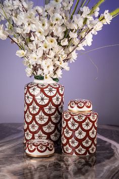 a vase with white flowers in it sitting on a table next to an object that looks like a canister