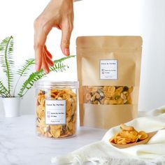 two bags of food sitting on top of a table next to a potted plant