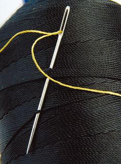 a needle is hooked up to a black piece of fabric with yellow thread on it