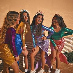 four girls dressed in shiny outfits posing for the camera