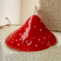 a red ceramic object sitting on top of a white wall next to a window sill