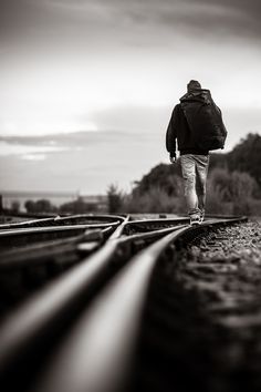 a person walking down train tracks with a backpack on their back and the words in arabic above them