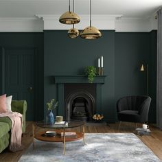 a living room with dark green walls and wooden floors, two chairs, a coffee table, and a fireplace