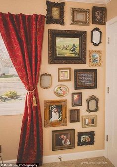 there are many pictures on the wall in this room with red drapes and curtains