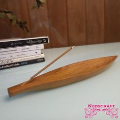 a wooden paddle sitting on top of a table next to some books and a vase