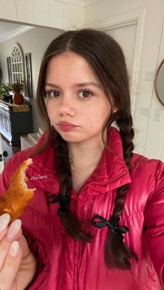 a woman in a pink jacket holding a piece of food