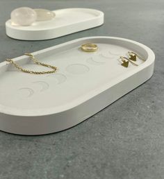 a white tray with two rings on it and a pair of gold earring hooks