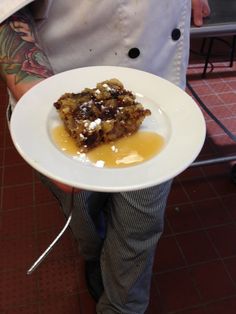 a person holding a plate with food on it in his hand and wearing an apron