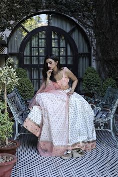 This peach and white poly paper silk lehenga has glitter flower motifs spread all over.  It is paired with an embroidered raw silk blouse and an embroidered net dupatta. White Cutdana Sharara In Tissue Silk, White Anarkali Tissue Silk Choli, White Anarkali Choli In Tissue Silk, White Tissue Silk Choli For Party, Peach Choli With Sheer Dupatta For Weddings, Peach Dupatta With Cutdana For Navratri, White Tissue Silk Choli With Pallu, White Tissue Silk Choli With Pallu Detail, White Anarkali Lehenga In Tissue Silk