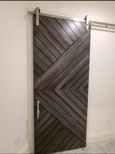 a wooden door with metal handles in a white walled room that is decorated with wood planks