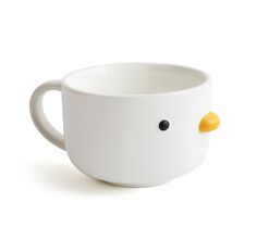 a white coffee cup with a yellow ducky head on it's side and black eyes