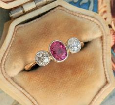 three diamond and pink tourmaline rings in a velvet case on top of a piece of cloth