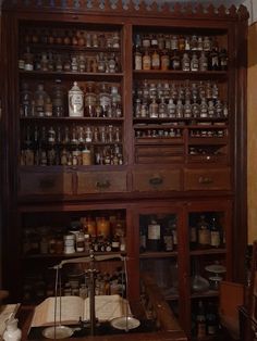 an old wooden cabinet filled with lots of jars and other items on display in a room