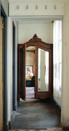 an open doorway leading to a bedroom with a large mirror on the wall and wooden furniture