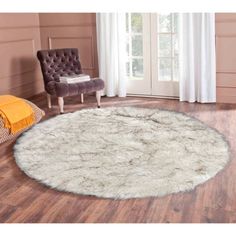 a large round rug in the middle of a room with wooden floors and white curtains