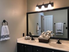 a bathroom with two sinks and a large mirror over the sink is lit by three lights