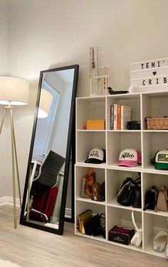 a mirror sitting on top of a white shelf next to a lamp and purses